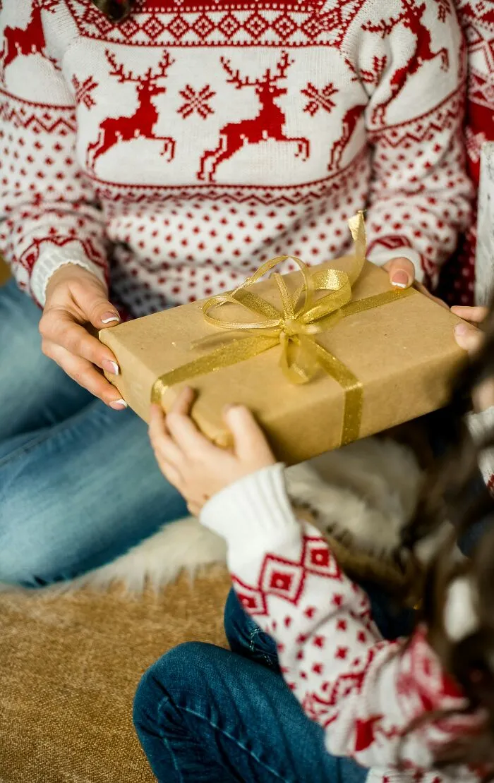 Hands exchange a wrapped gift, representing family connection amidst challenging under my roof rules.
