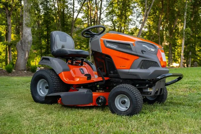 An orange lawn tractor parked on a lush green lawn, under my roof rules backfired on parents.