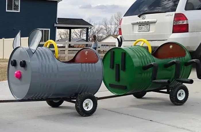 Two barrel-shaped carts, one gray mouse and one green bug, made from old junk for kids to ride, showing creativity.