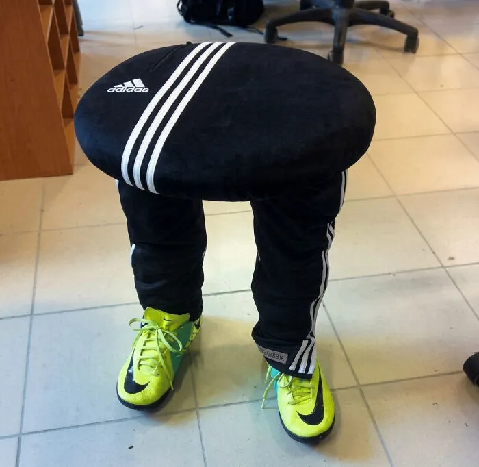 A stool designed to look like a person wearing Adidas sweatpants and bright yellow Nike shoes, a bizarre furniture item.