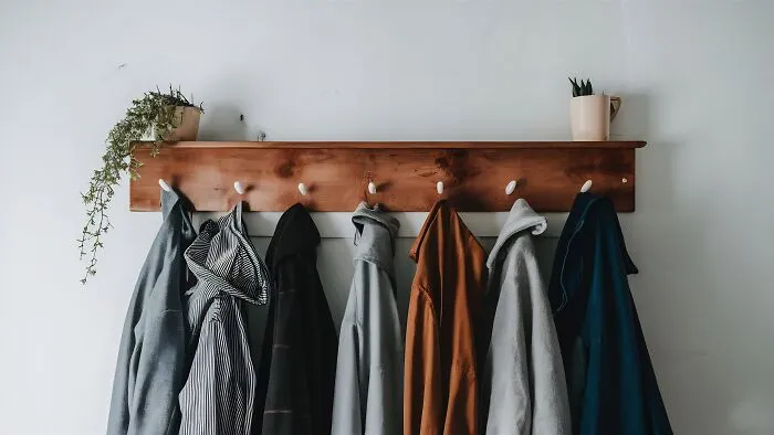 A coat rack with various coats hanging on it, illustrating house etiquette among guests.