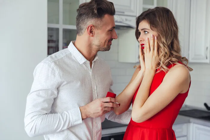 A man proposing to a surprised woman in a kitchen. Sometimes a first date has shocking red flags.