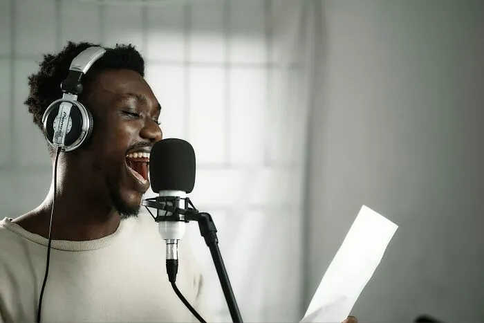 A man wearing headphones sings into a microphone, embodying moments men give partners an ick they can't get over.
