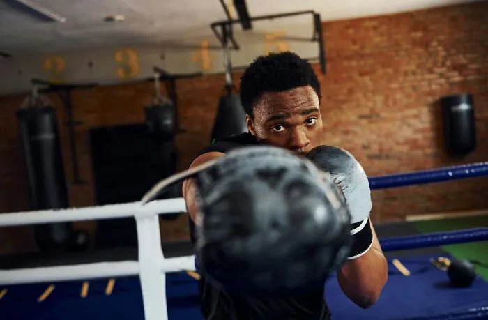 A male boxer in a ring, wearing gloves and looking intense, showing an ick from men to their partners.