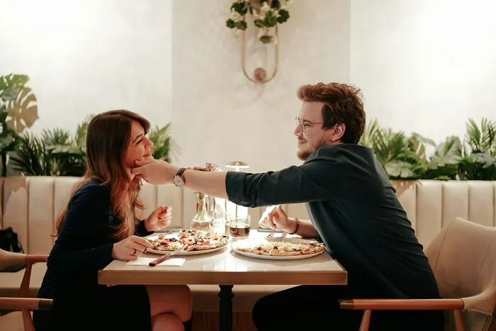 A man lovingly touching his partner's face during a meal, illustrating men giving partners an ick.