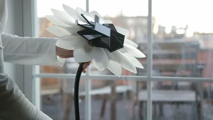 Hand holding a 3D printing kinetic flower with white petals, an amazing creation.