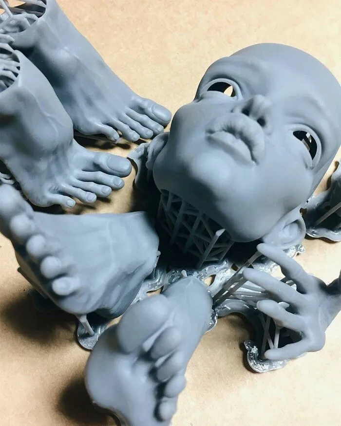 Unassembled grey 3D printing parts of a doll, including a head, hands, and feet, showing amazing creations.