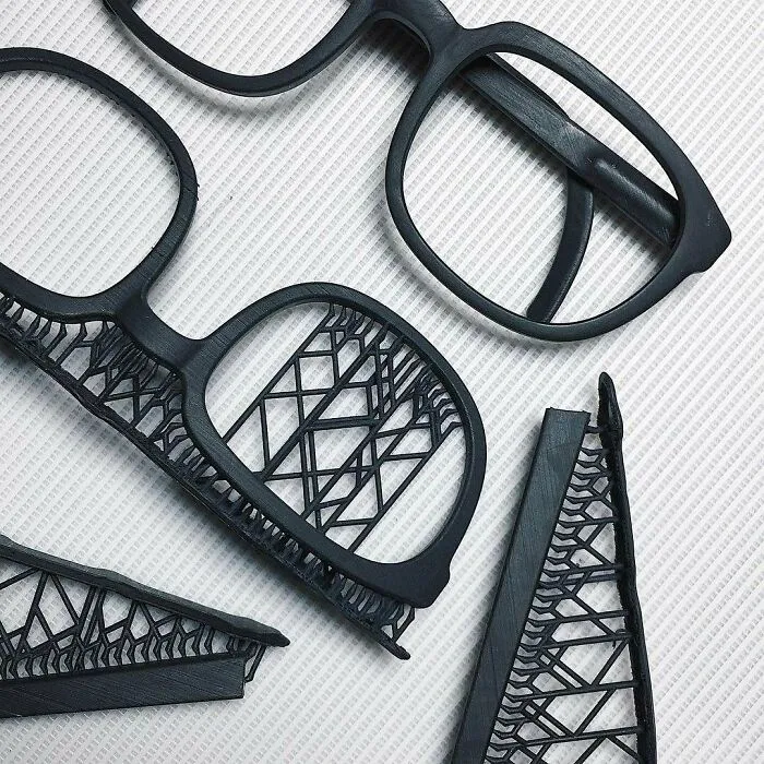 Amazing 3D printing creations: black glasses frames with intricate, delicate lattice designs.