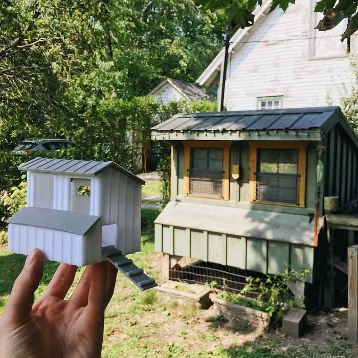A hand holding a small 3D printing model of a chicken coop next to a real full-sized coop, showcasing amazing creations.
