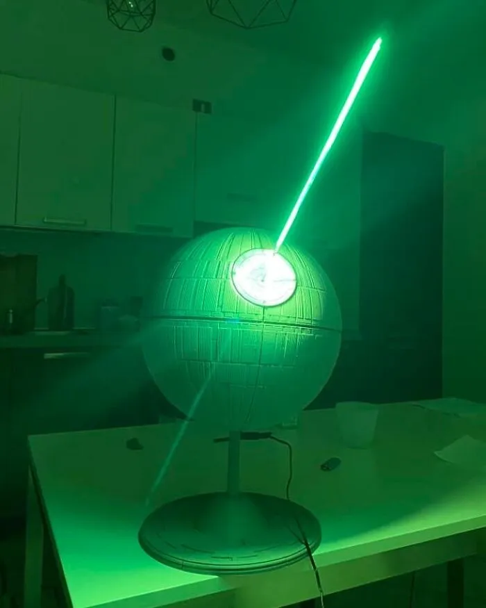 A 3D printing creation of the Death Star emitting a green laser beam, an amazing 3D printing creation by fans.