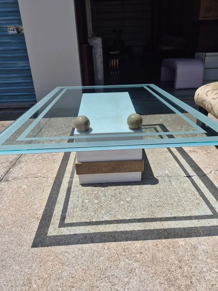 An outdoor shot of a bizarre furniture design, featuring a glass-top table with stone spheres.