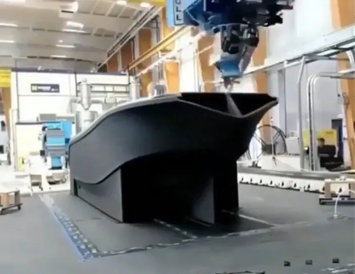 A large industrial machine uses 3D printing to create a boat hull, demonstrating amazing 3D printing creations.