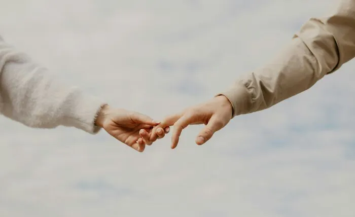 A close-up of two hands reaching out to touch, symbolizing the connections within international couples facing culture shocks.