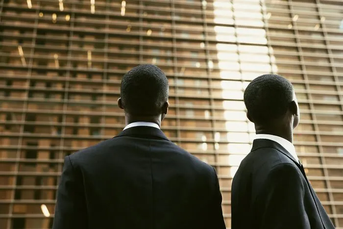 Two men in suits looking at a modern building, symbolizing the serious and sometimes funny aspects of last will stories.