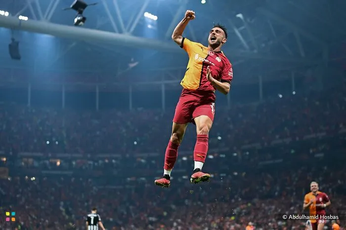 A soccer player in a red and yellow jersey jumps in celebration on a field in an award-worthy photo.