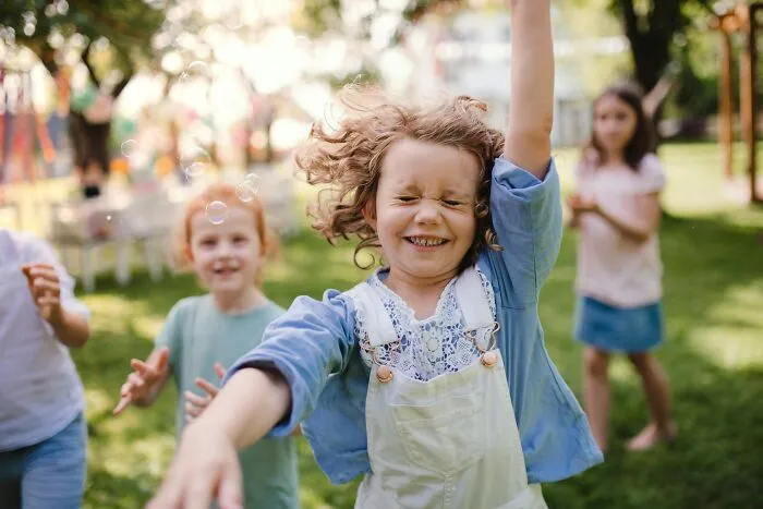 Happy daughters playing outdoors with bubbles. Dads' understanding of women changed.
