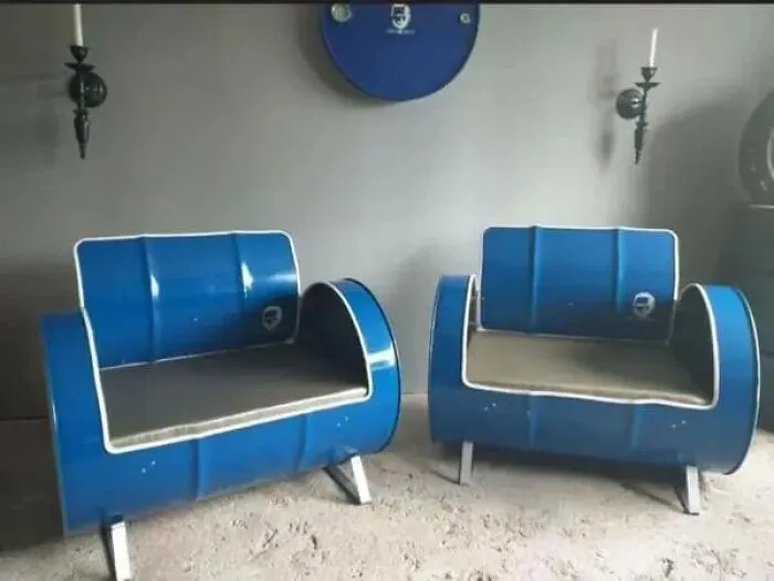 Two bizarre blue furniture designer armchairs made from repurposed barrels with white cushions.