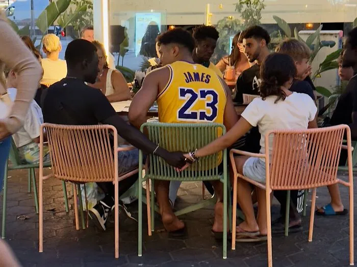 Fotos accidentales: personas tomadas de la mano en una mesa de café al aire libre, un momento justo de conexión.