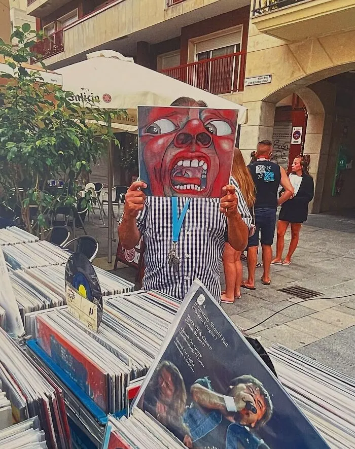 Divertida foto accidental de un hombre que se esconde detrás de la portada de un disco en un mercadillo.