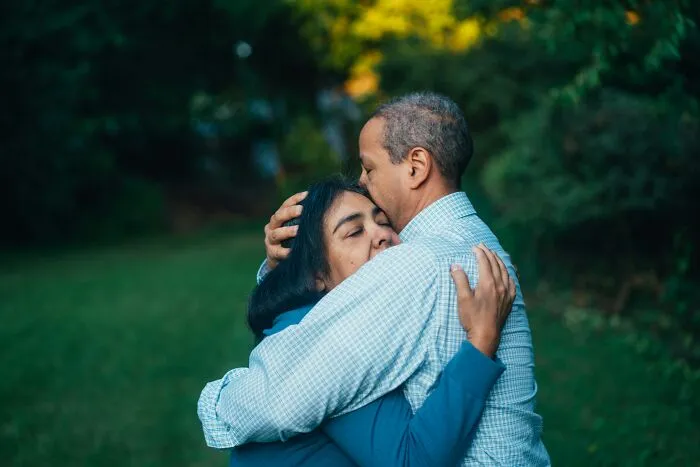 A middle-aged couple sharing a tender hug outdoors, depicting the realities of being married.