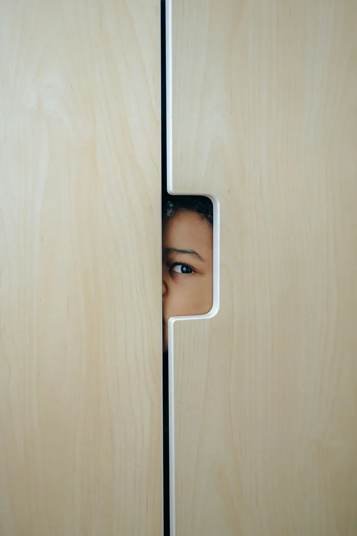A child's eye peeking through a door crack, suggesting a time parents were terrified of their own children.