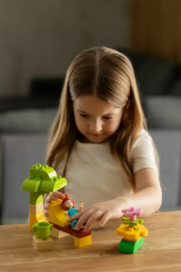 A little girl playing with building blocks and dolls, an innocent moment before parents were terrified.