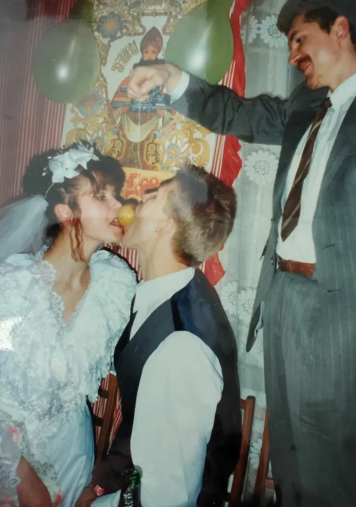 A bride and groom sharing a fruit, an unusual and silly wedding photo moment.