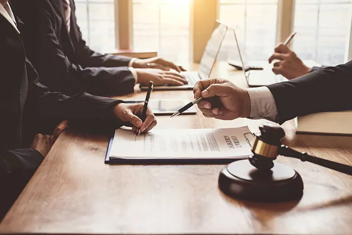 Divorce lawyers at a table, signing documents, discussing instant karma in their most satisfying cases.