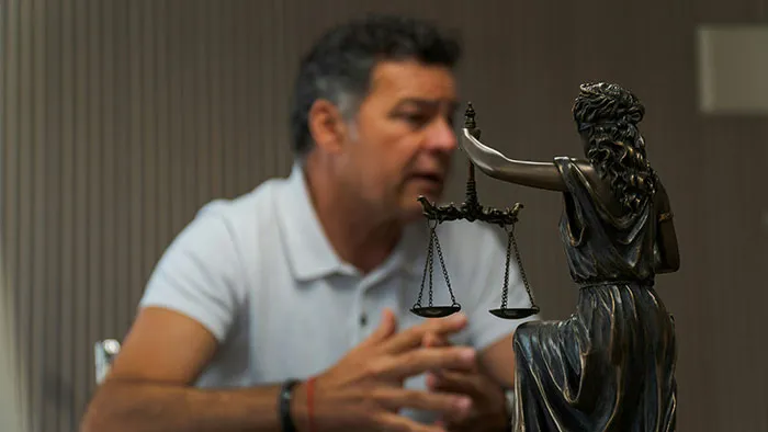 A divorce lawyer discusses a case, with a statue of justice in the foreground, signifying instant karma.