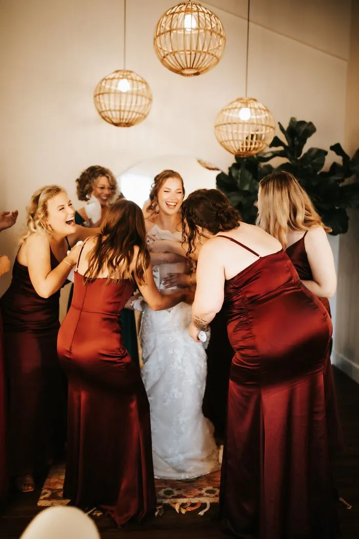 Bridesmaids laughing while helping a bride get ready, capturing funny wedding moments.