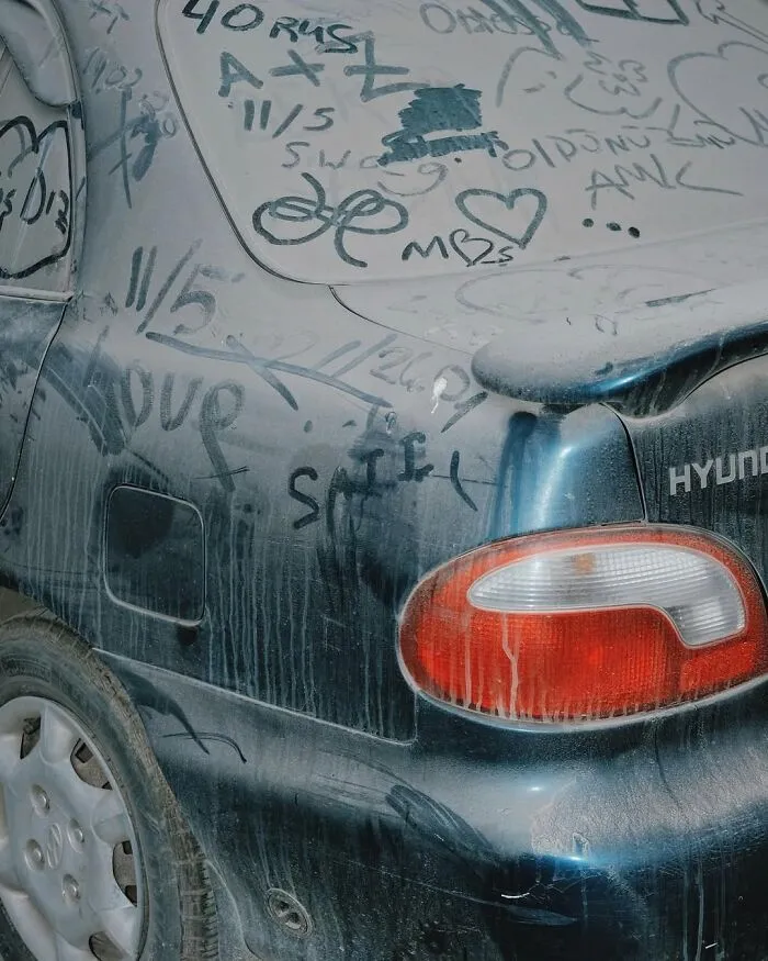 A dusty car covered in well-timed street shots and graffiti, showcasing urban art and spontaneous expressions.