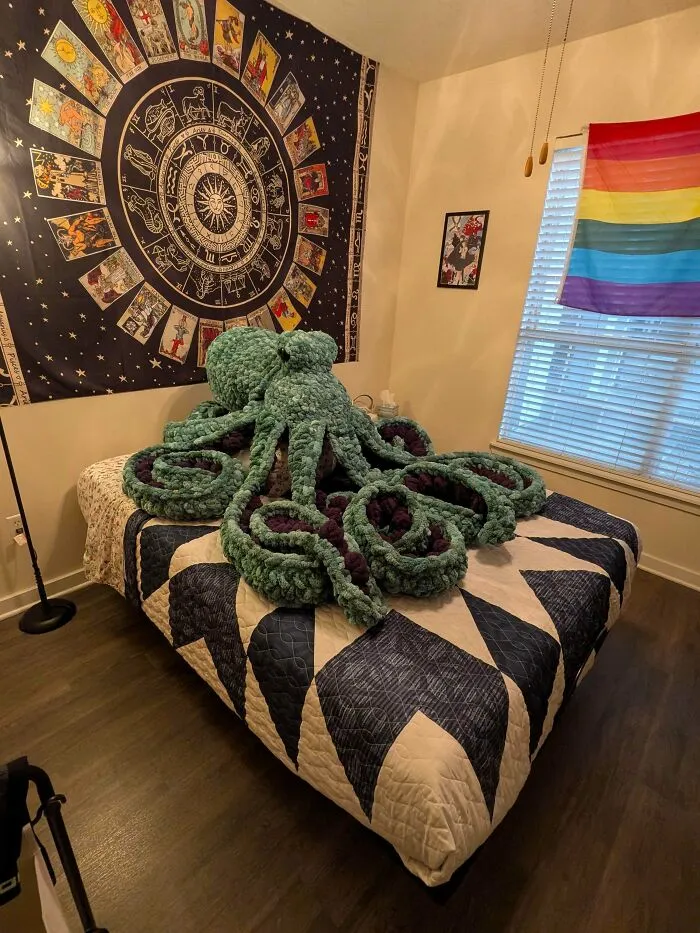 Large crochet octopus sitting on chevron patterned bed in a decorated room