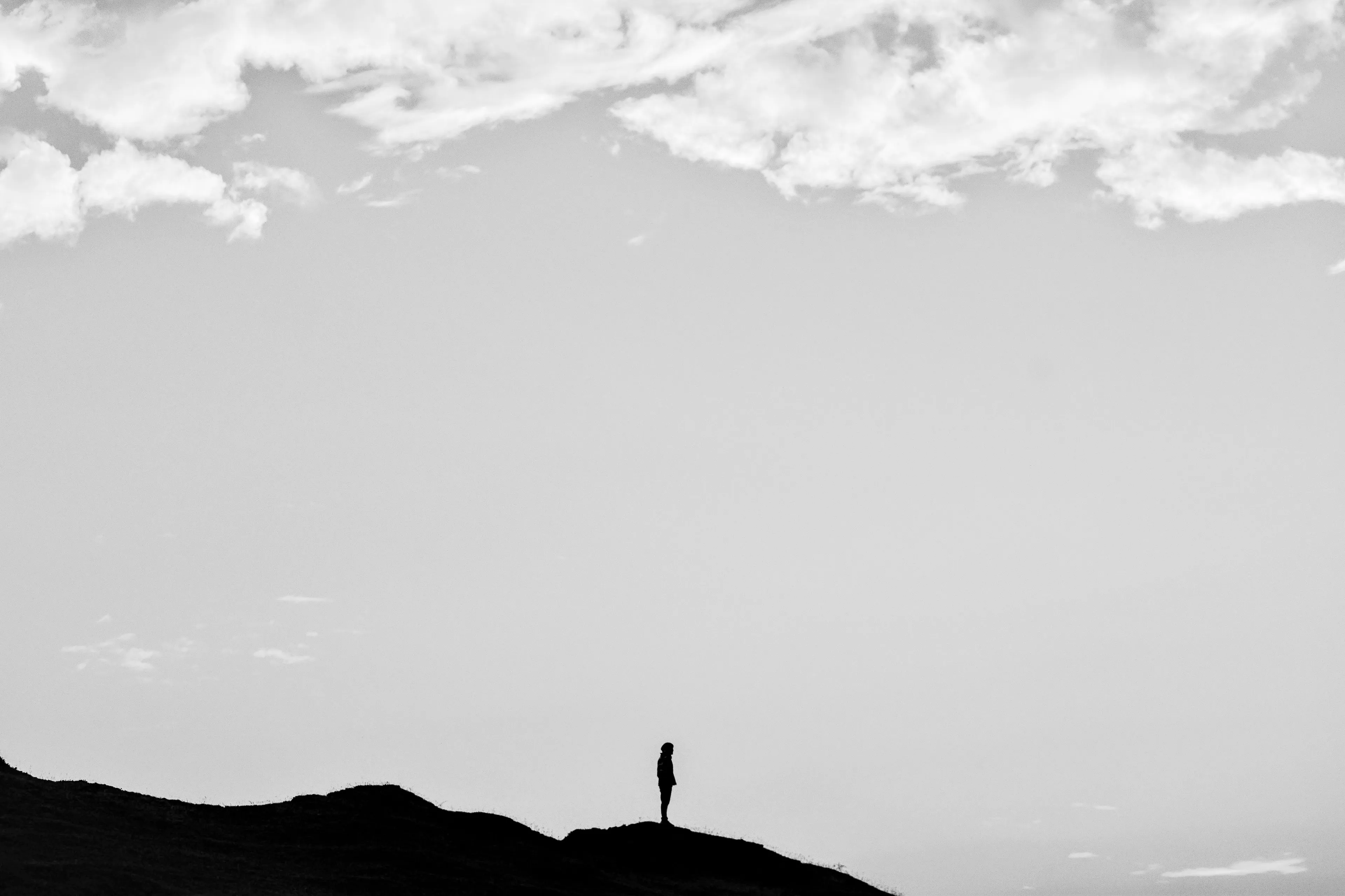 Monochrome silhouette of a person standing on a hill against a wide, cloudy sky, perfect for discovering your Japanese Cube Personality Type.