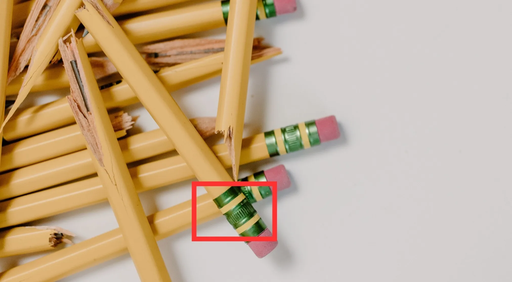 A pile of yellow broken pencils, with a red box highlighting the eraser's ferrule. Match A Picture To A Difficult Word.
