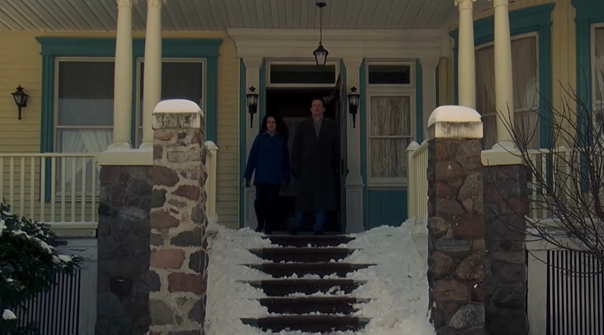 A couple walking down snowy steps of a house, representing a film ending scene.