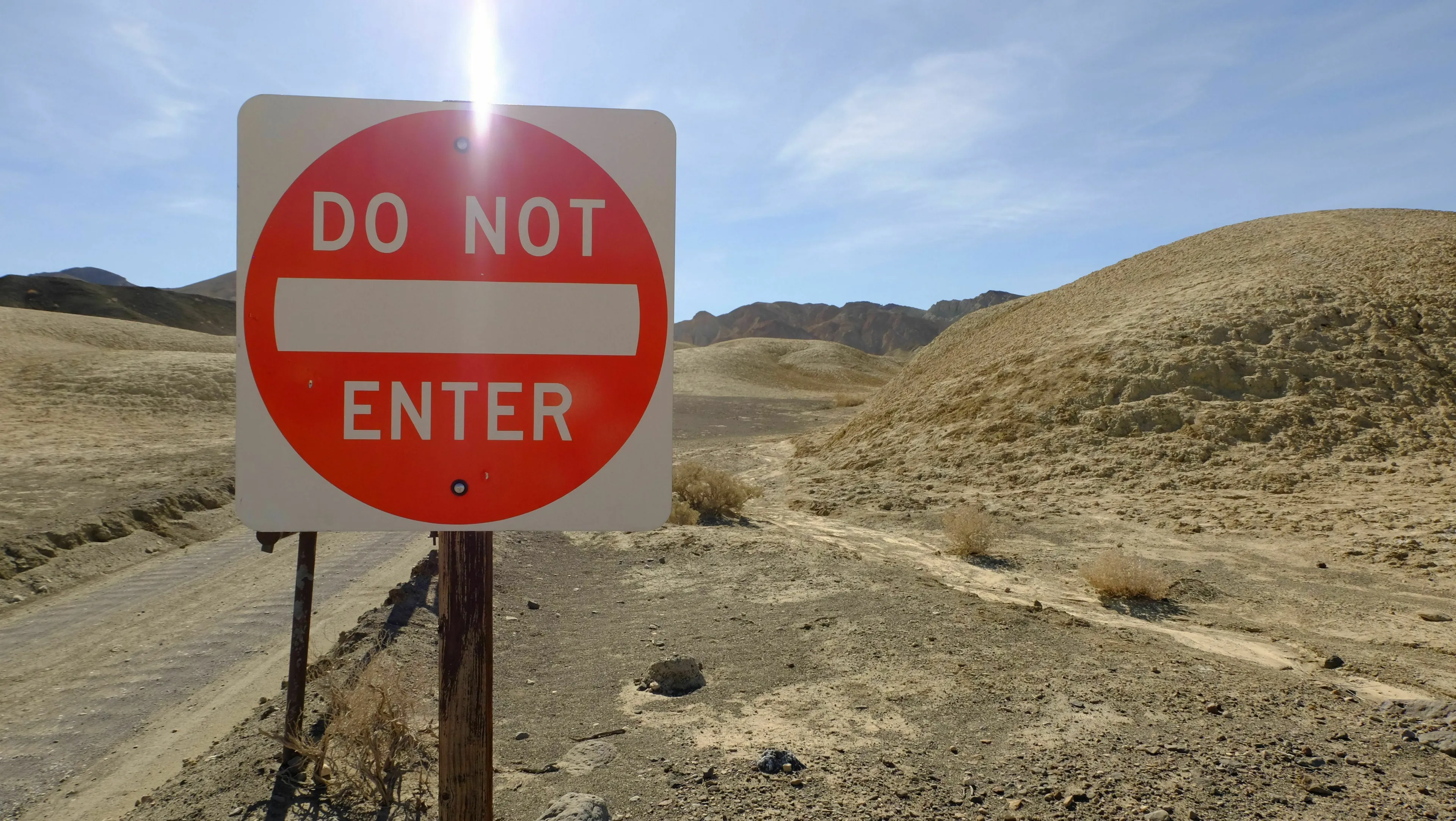 A bright red Do Not Enter sign stands in a dry, barren landscape, challenging a mythological trickster's plan.