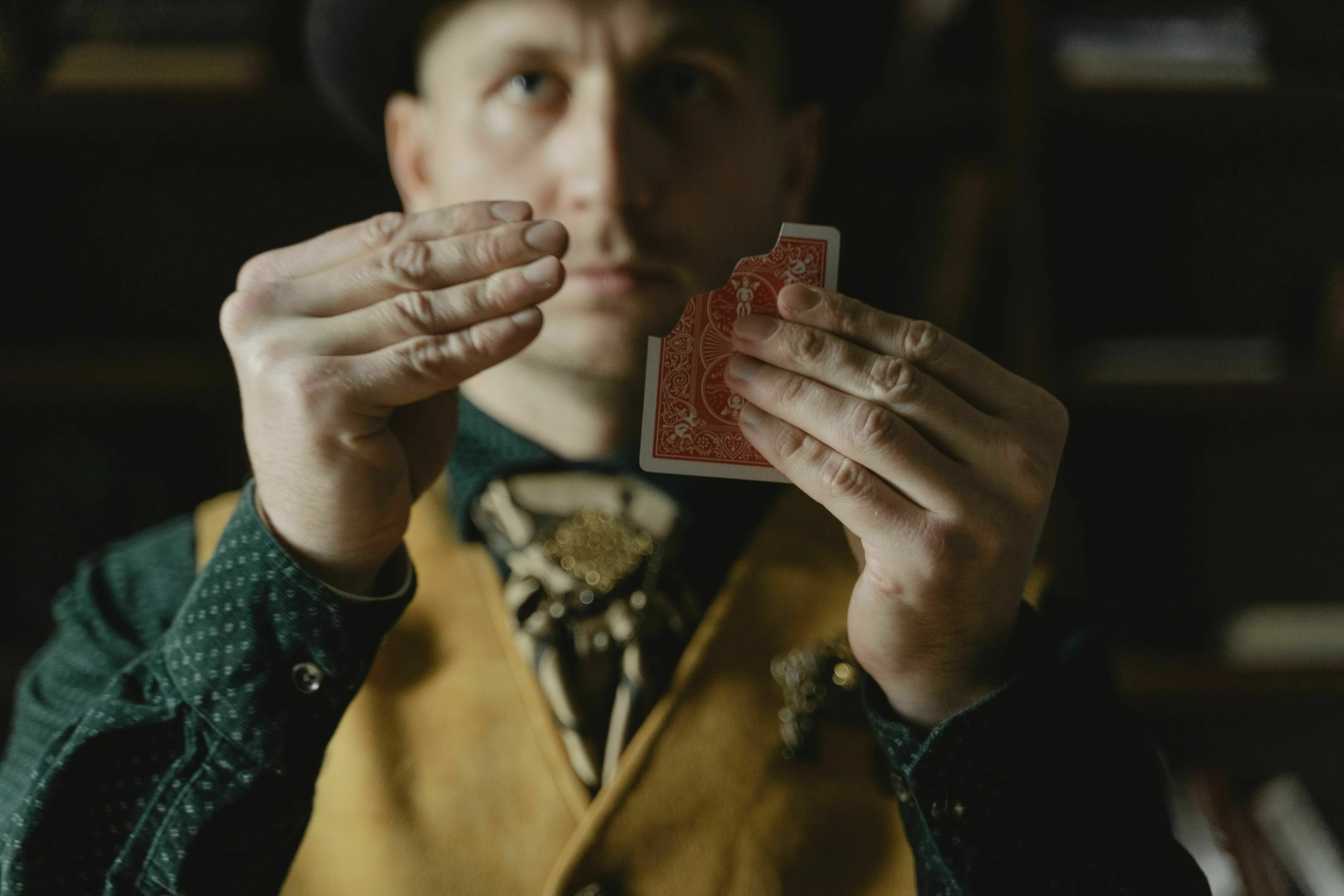 A magician holding a torn playing card, illustrating being outsmarted as a mythological trickster.