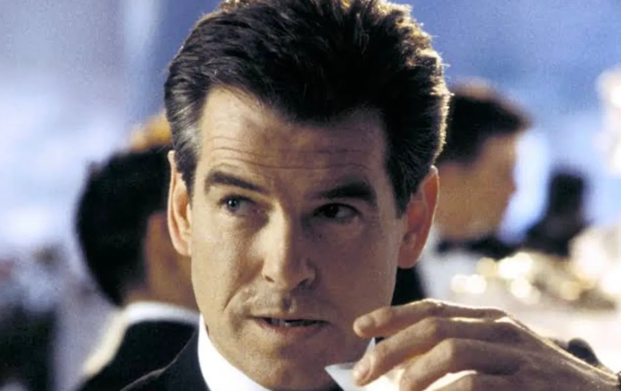 Close-up of Pierce Brosnan as James Bond, looking dapper in a suit, holding a drink. A general knowledge quiz.