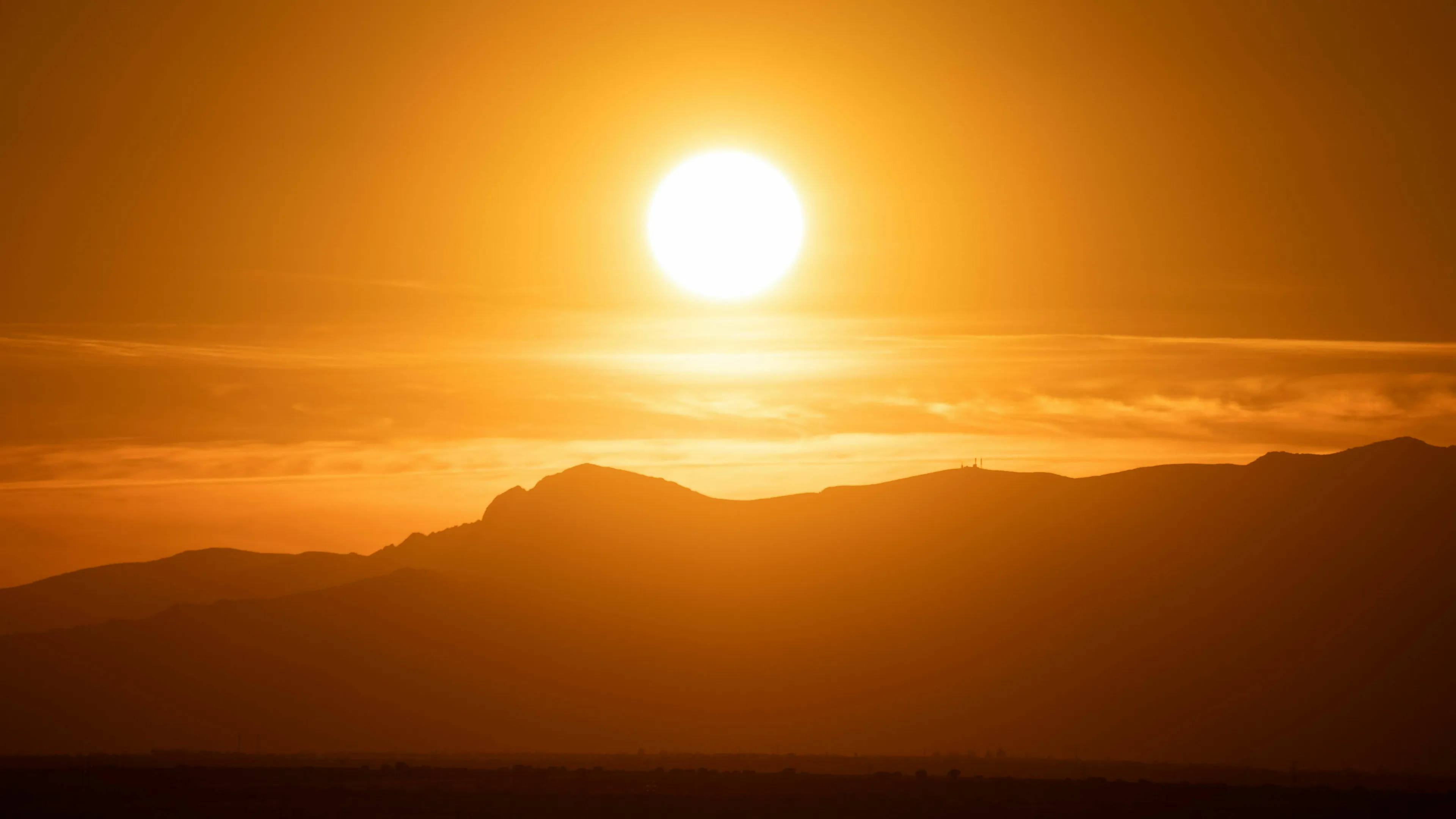 A vibrant orange sun setting over mountains, illustrating general knowledge about planets and the Sun.