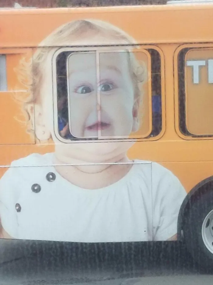 A baby's face on a bus ad is perfectly aligned with a window, creating an interesting and hilarious ad placement.