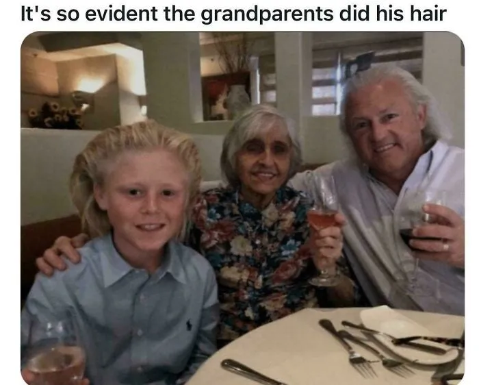 A young boy with an unusually styled, spiky blonde haircut, sitting between two older adults who are holding drinks, displaying bold hairstyles.