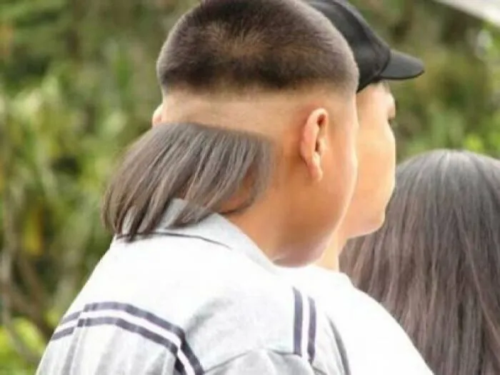 A young person with a short haircut on top and long hair cascading from the back, showcasing bold hairstyles.