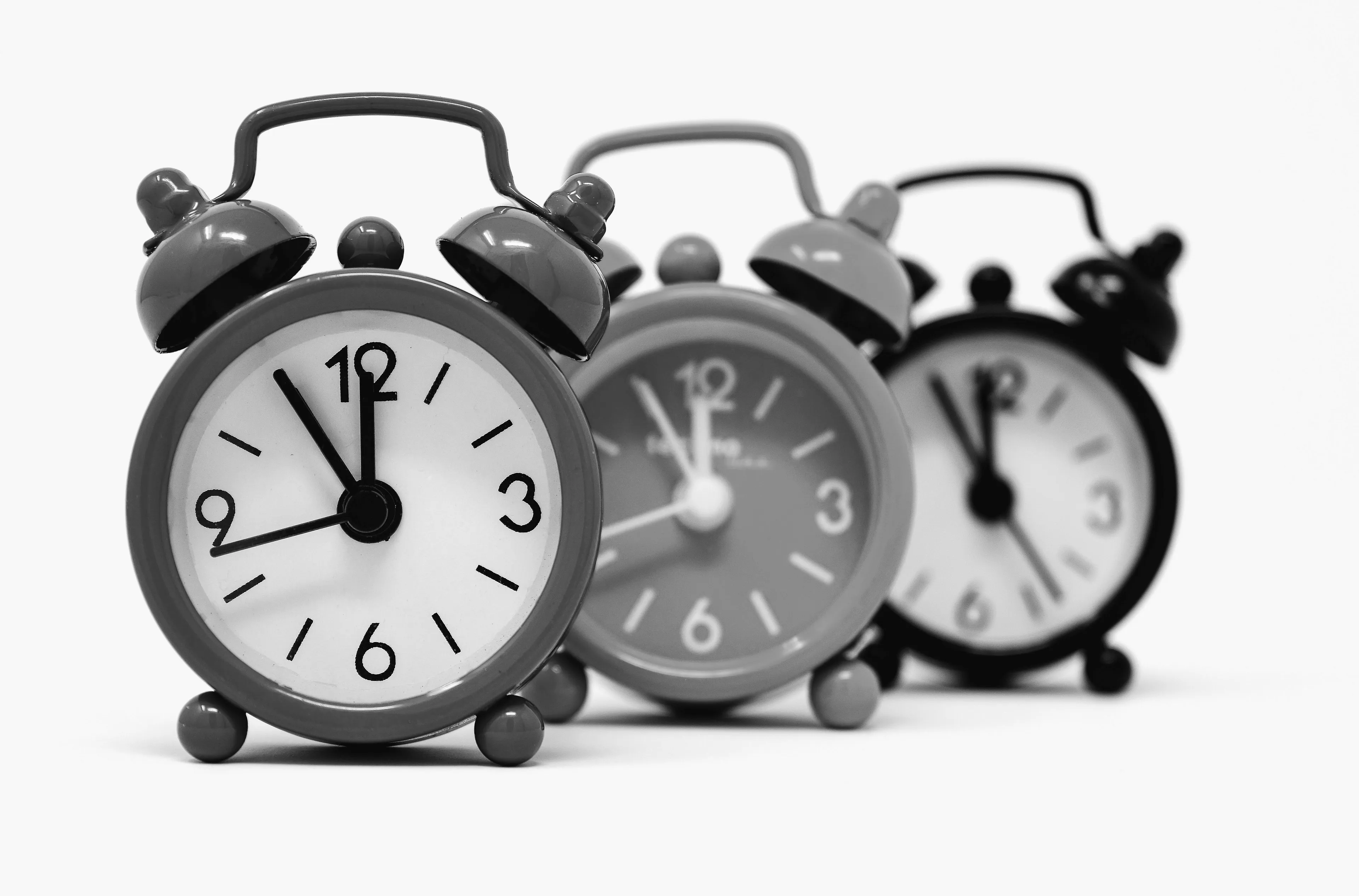 Three alarm clocks in a row, the closest one showing 11:30, symbolizing an angel number message.