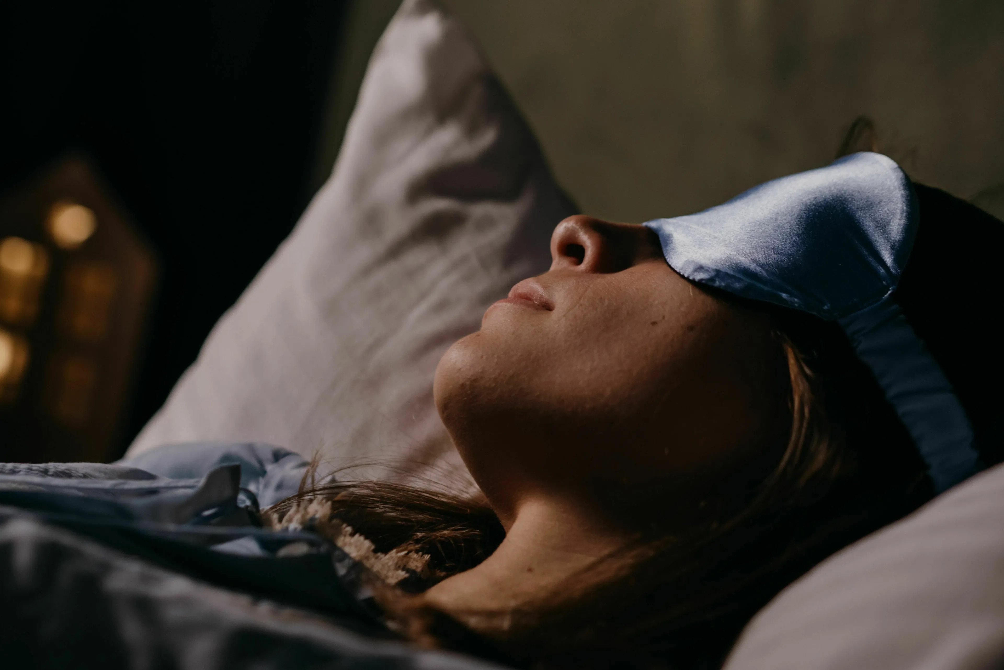 A person wearing a sleep mask in bed, dreaming about their Angel Number and what to do with it.