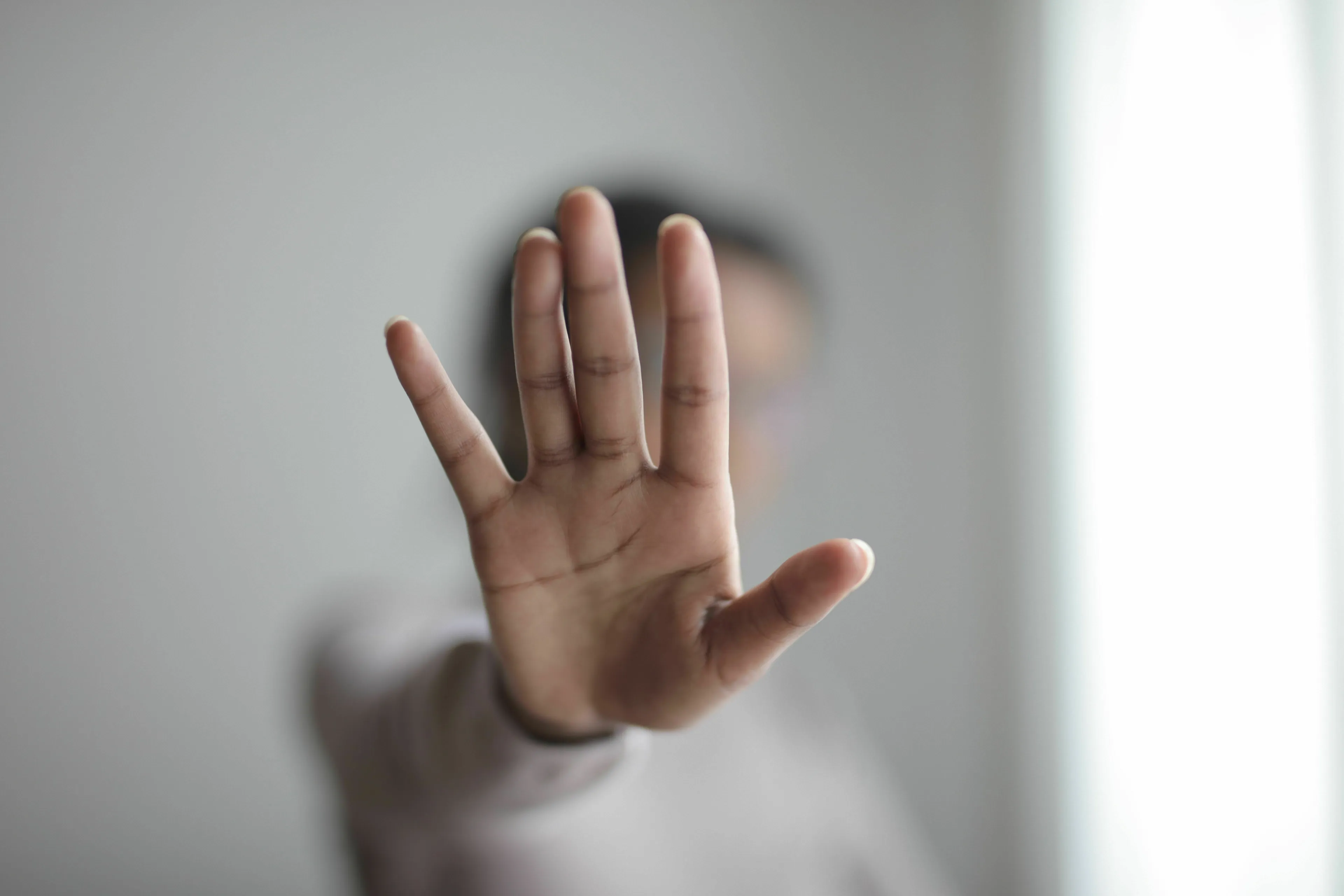 A person holding up a hand in a stopping gesture, regretting ignoring a strong instinct.