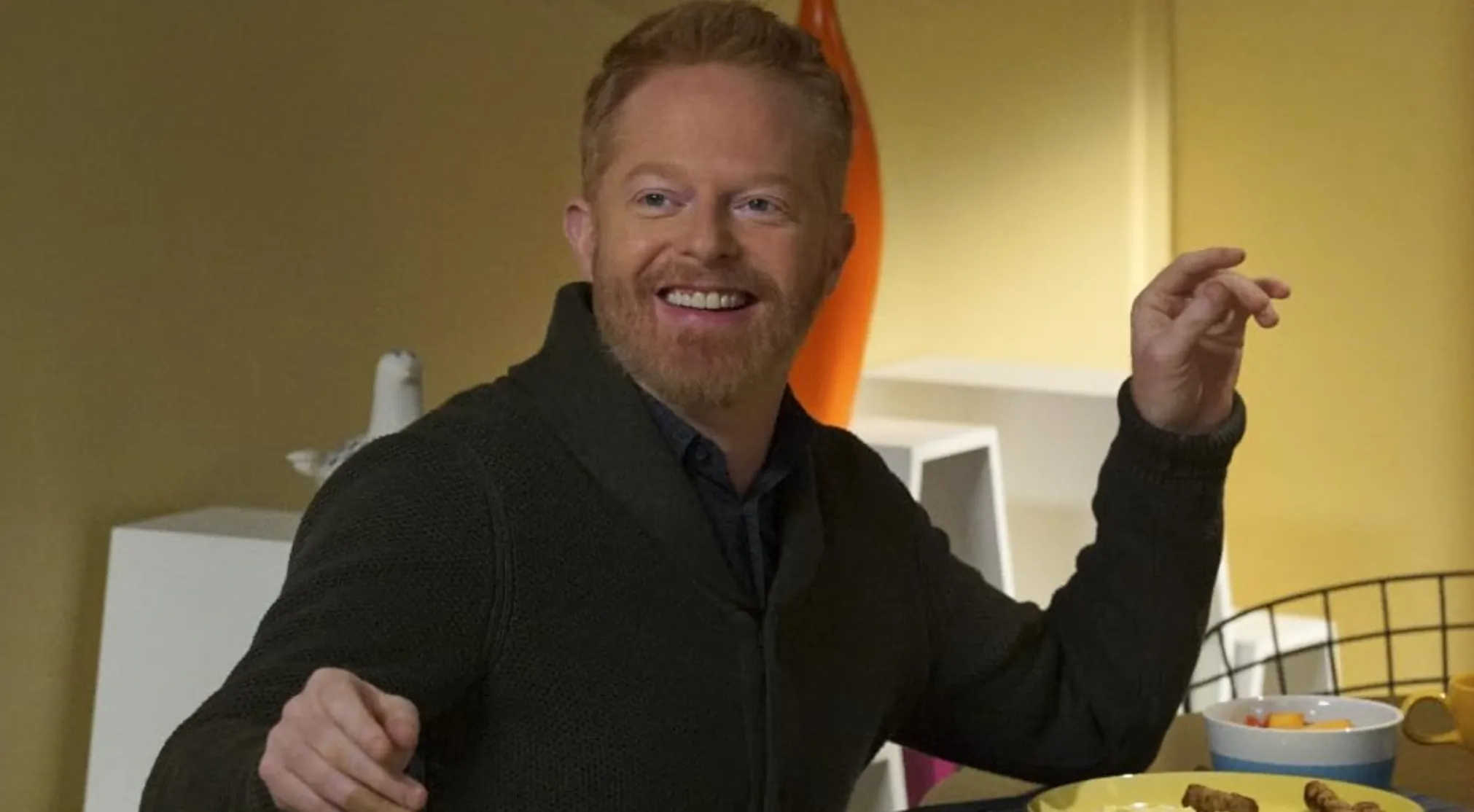 Jesse Tyler Ferguson as Mitchell Pritchett from Modern Family, smiling at a table, discussing his character's profession.