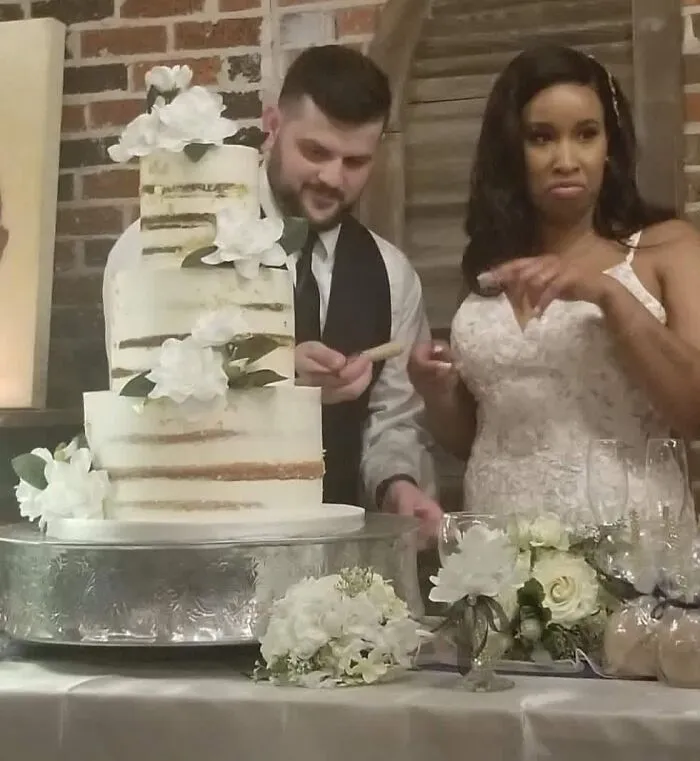 Funny wedding photo of a bride reacting to a groom cutting their iconic wedding cake.