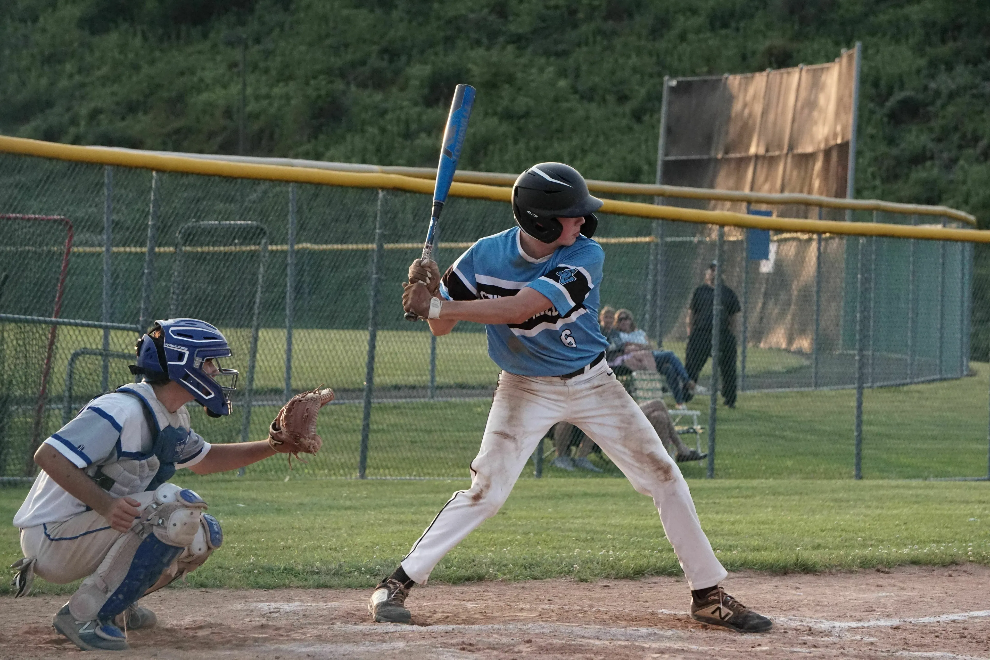 A baseball player at bat, with a catcher behind him, illustrating how many strikes make an out in a pub quiz.