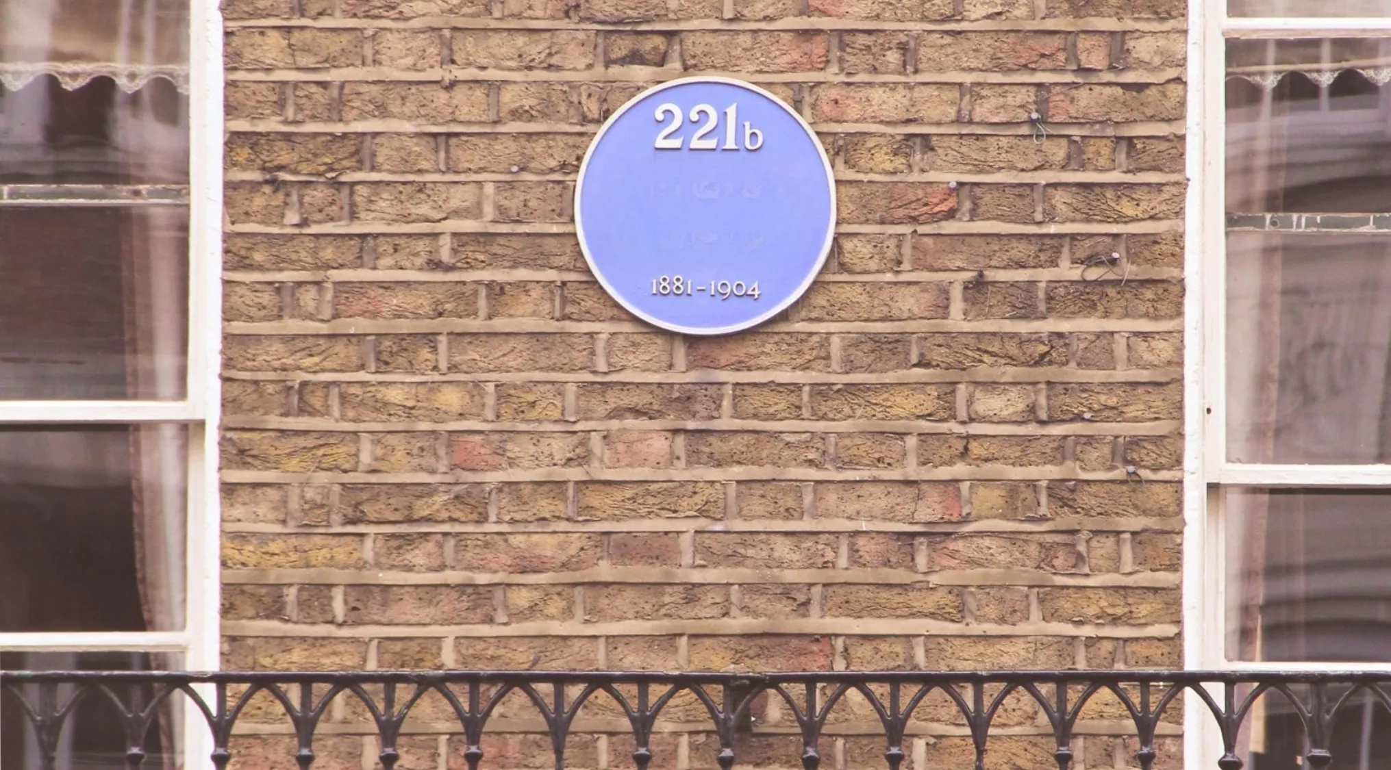 A blue plaque with 221B on a brick wall, part of a general knowledge pub quiz about a fictional detective.