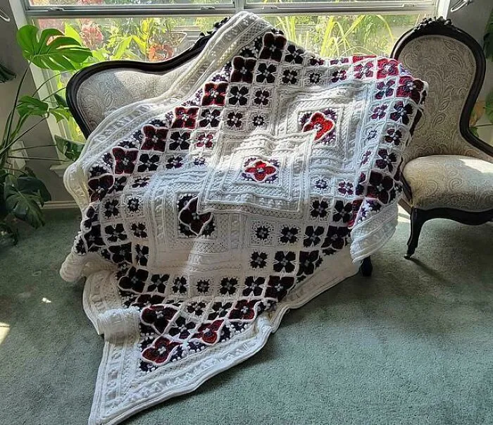 Crochet granny square blanket draped over vintage couch with floral pattern